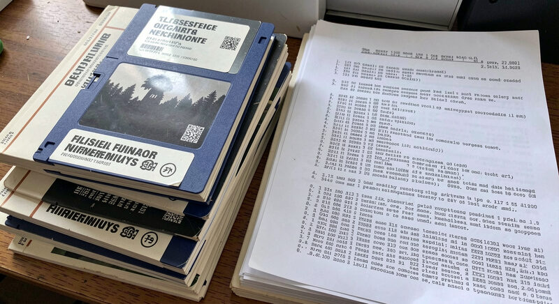A close view of a printed keyword index page on a desk beside a laptop showing a code editor, with a period at the end of a highlighted statement line, lit by an ordinary desk lamp in a small office.